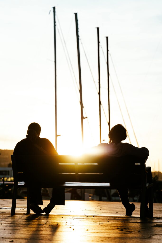 Silhouetted couple enjoying a peaceful sunset at Barcelona harbor, capturing a serene and romantic moment.